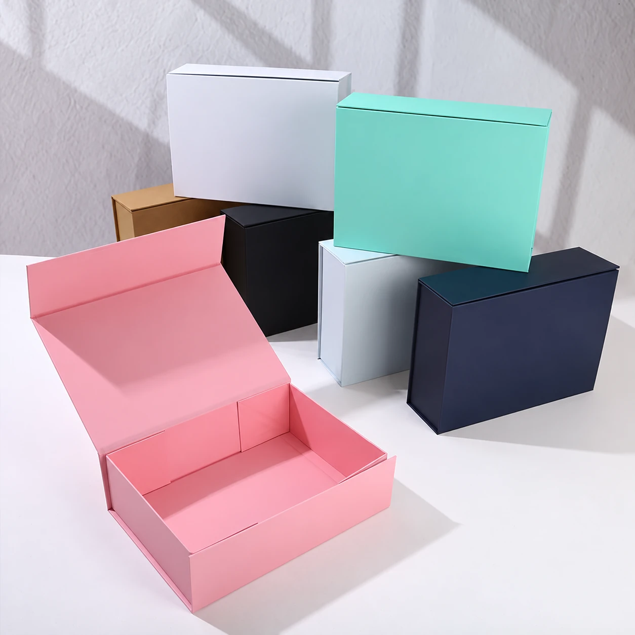An open pink magnetic gift box with six closed boxes in different colors